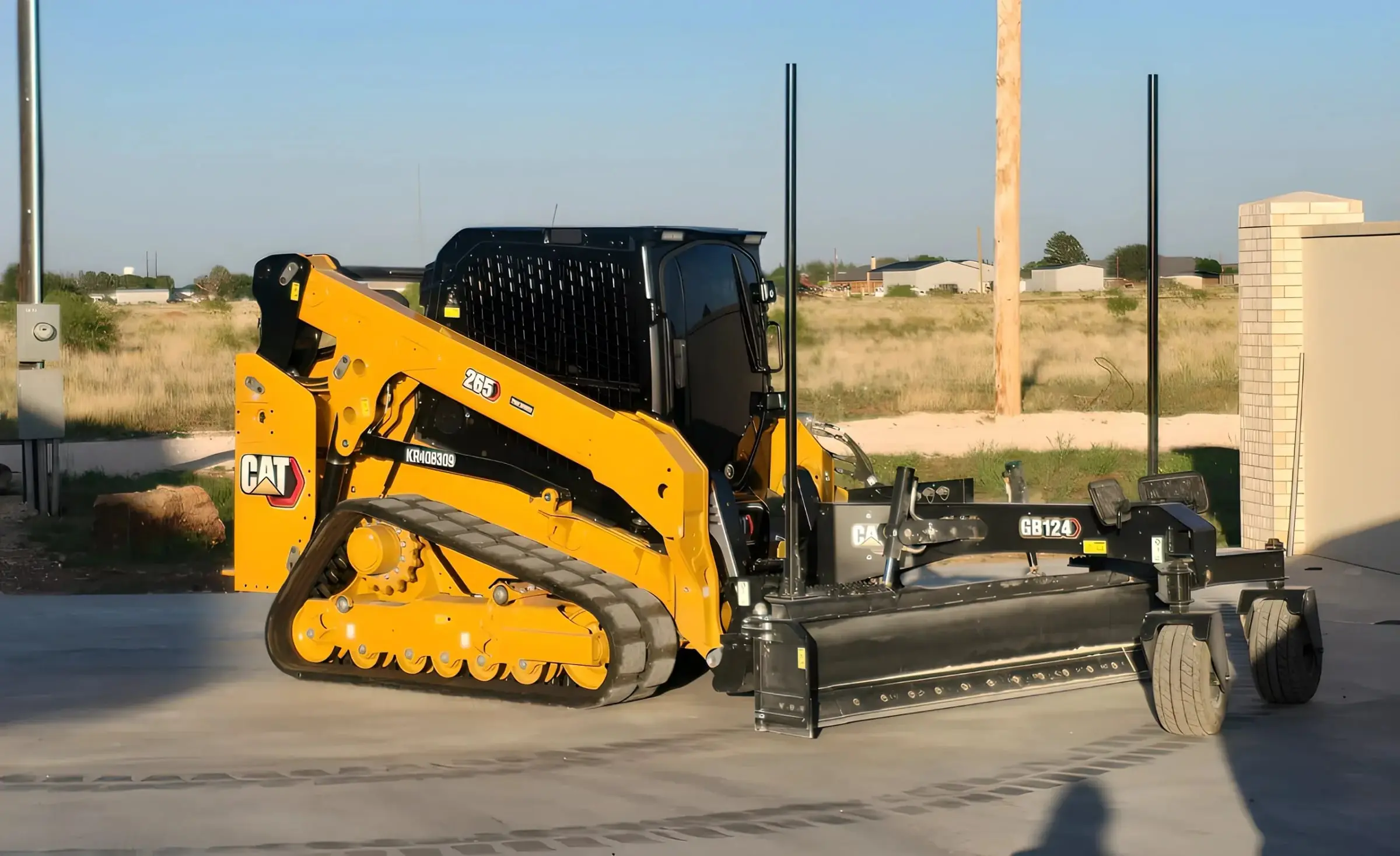 Close view of a compact track loader with a laser grade box attachment parked on concrete
